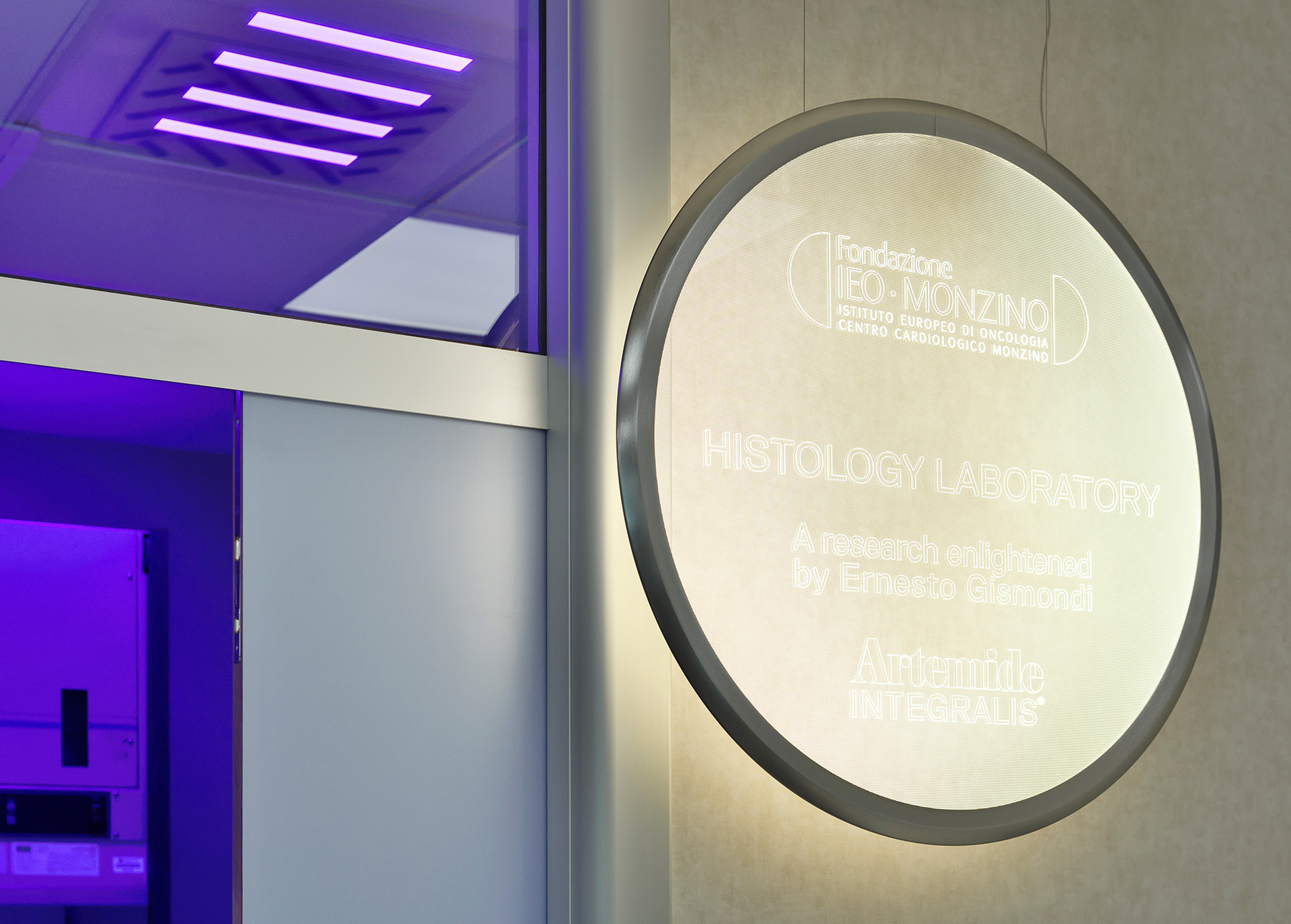 Artemide Integralis lighting in the Histology Laboratory at Fondazione IEO-Monzino, with purple ceiling lights and a glowing circular sign.