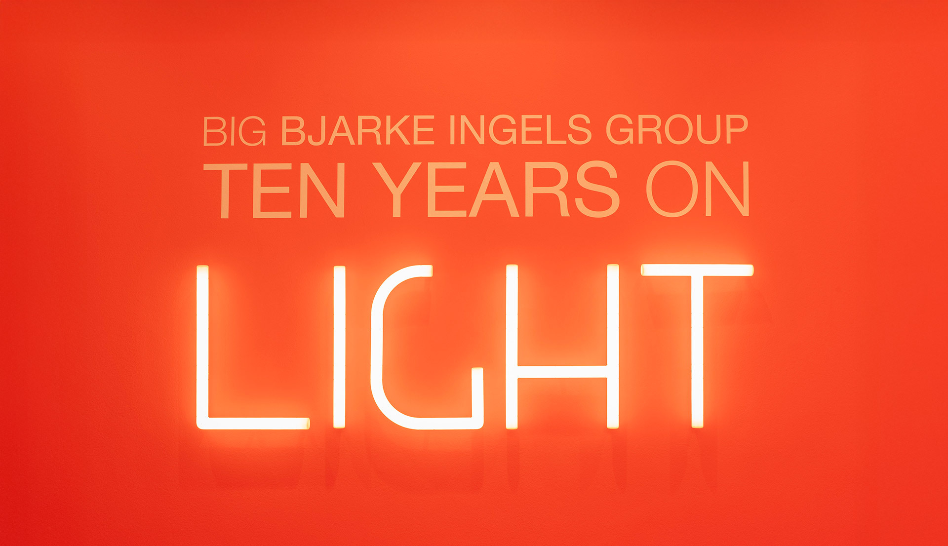 Scritta luminosa “Ten Years on Light” realizzata con Alphabet of Light, su sfondo rosso.