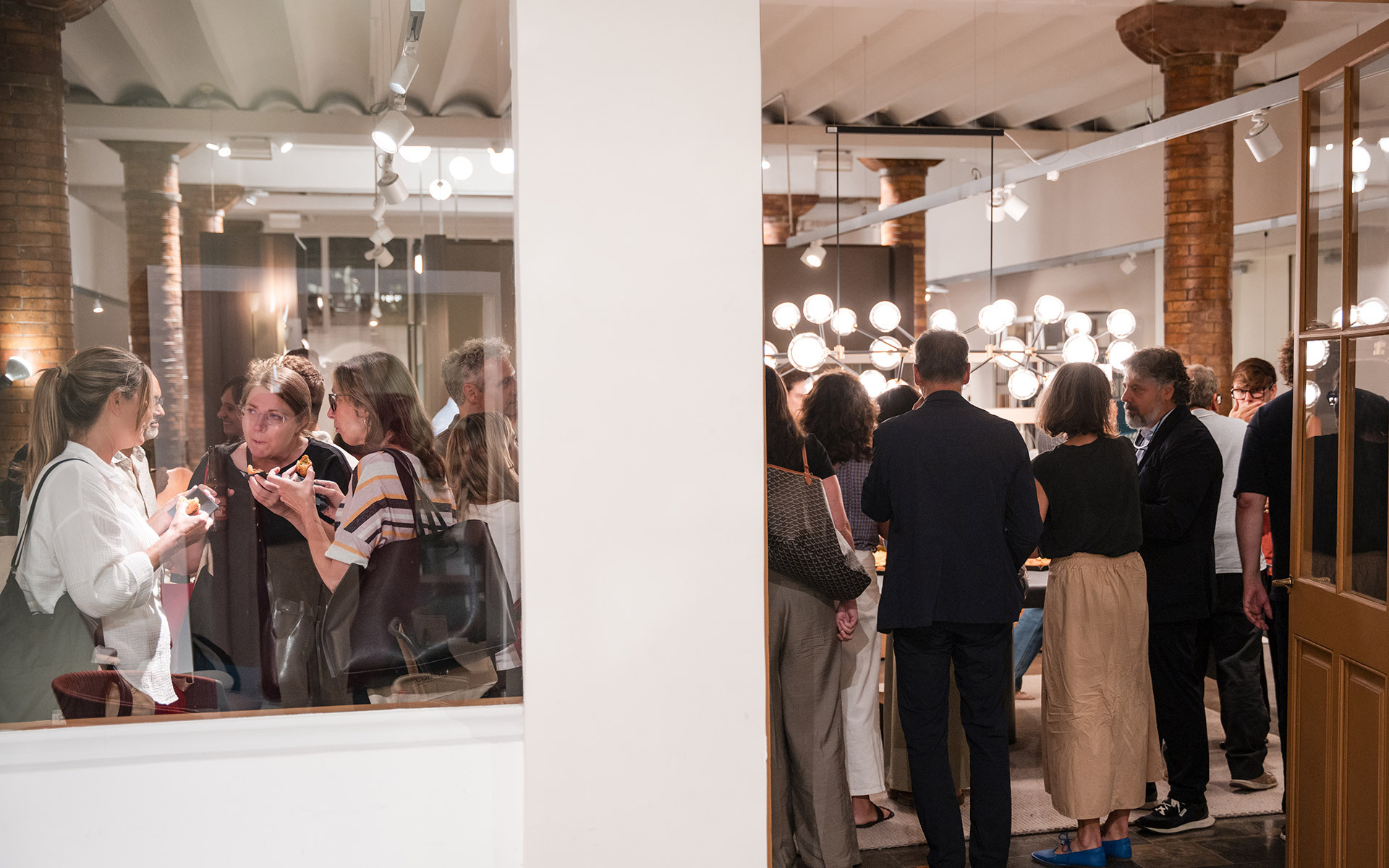 Gli ospiti si riuniscono a un evento Artemide, con lampade a sospensione a globo sferico che illuminano l'elegante spazio interno.