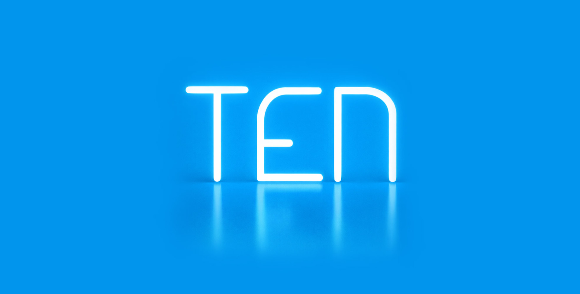 Scritta luminosa “TEN” realizzata con Alphabet of Light, su sfondo azzurro con riflesso sulla superficie lucida.