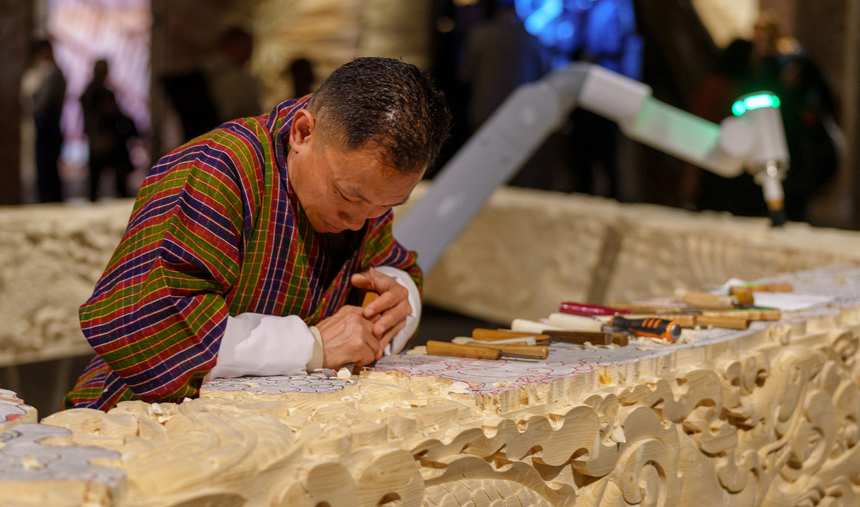 Artista bhutanese scolpisce una scultura in legno in collaborazione con un robot.