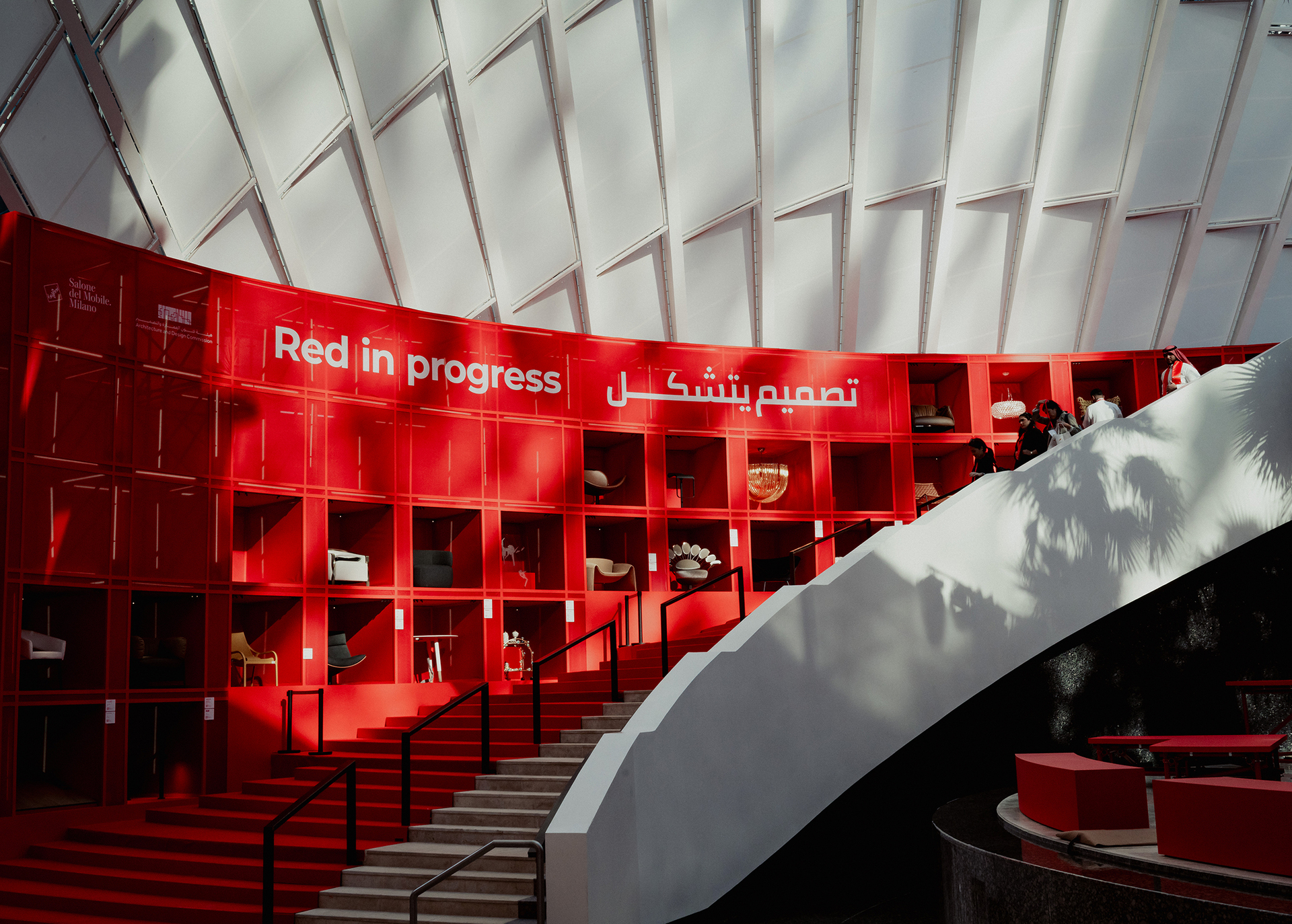 Photo of the installation for Salone del Mobile.Milano in Riyadh: a red cell-like structure displaying the products, accompanied by a red staircase that follows its profile.