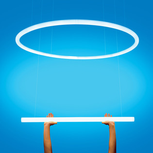 Sospensione circolare e lineare Alphabet of Light sorretta da due mani su sfondo azzurro. Foto di Pierpaolo Ferrari.