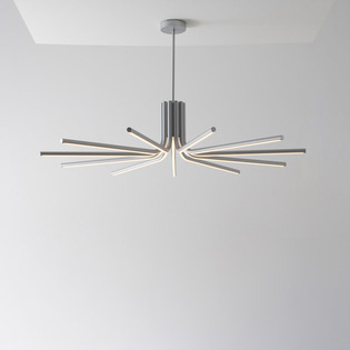 Lampada a sospensione Veil con bracci luminosi disposti a raggiera, installata in un interno minimal dalle pareti chiare.