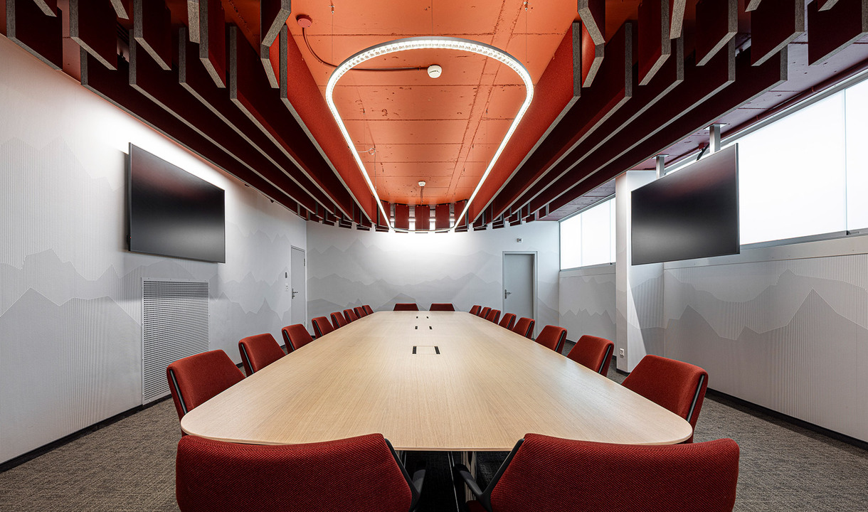 Suspended Somnĭum System light fixture installed above the central table in a meeting room.