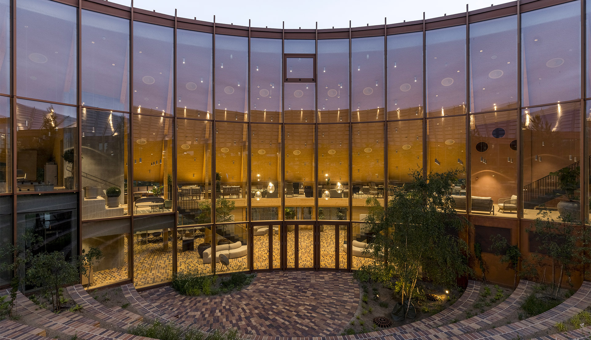 Stellar Nebula illuminates the interiors visible through the façade at dusk.
