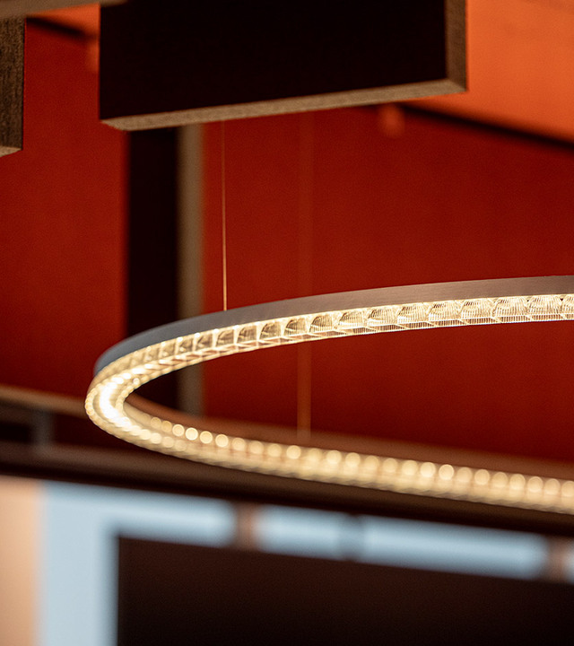 Detail of the suspended Somnĭum System light fixture illuminated in a meeting room.