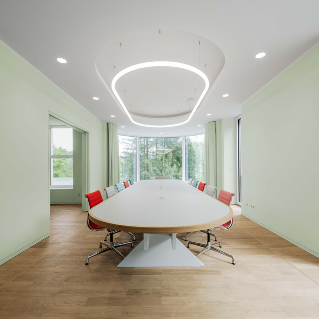 Image of the meeting room with a large table and many coloured chairs, all lit by Alphabet of Light System.