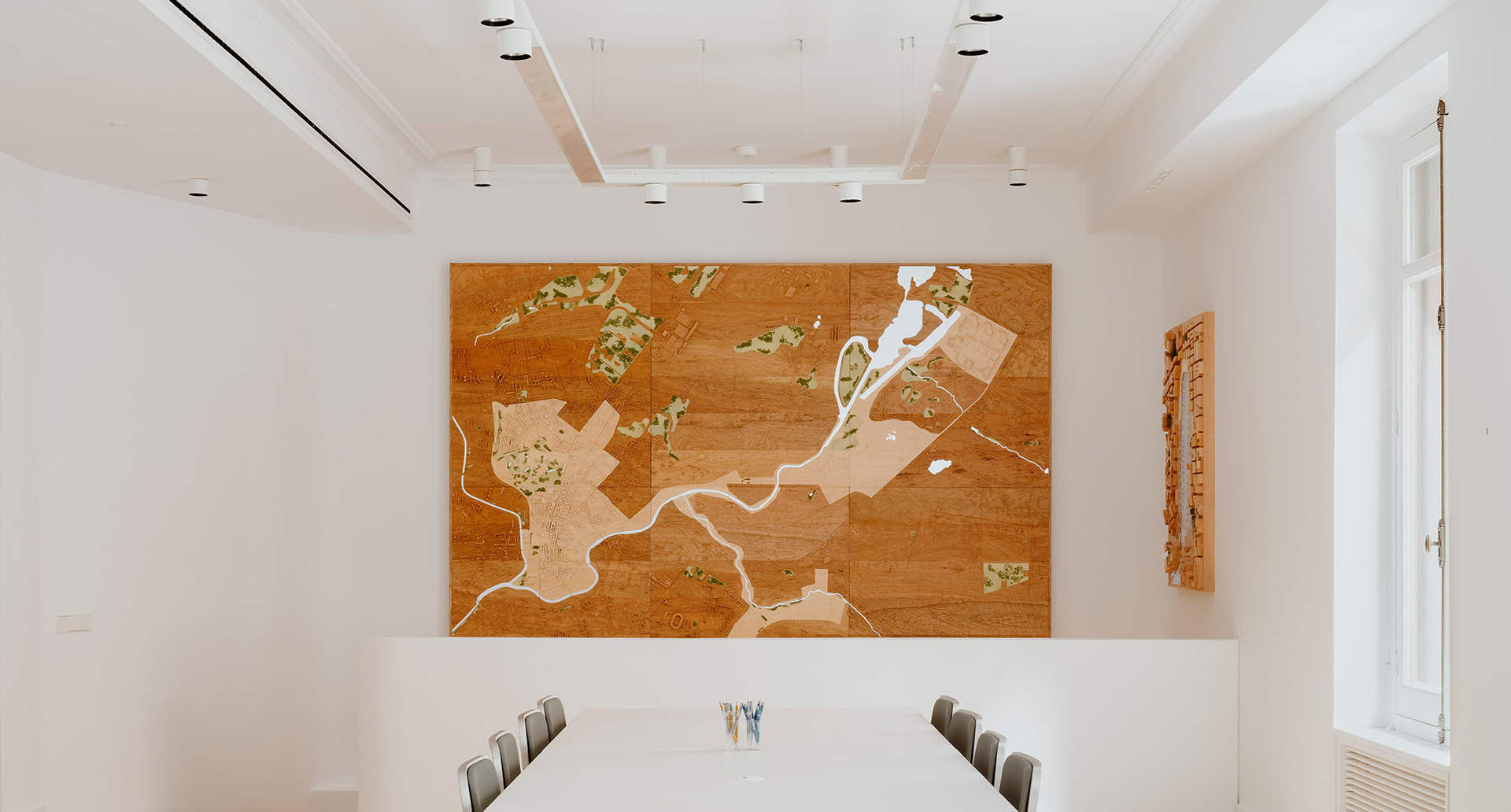Room at the Norman Foster Foundation with tables, chairs, and a wall map, illuminated by Hoy System and Hoy Spot.